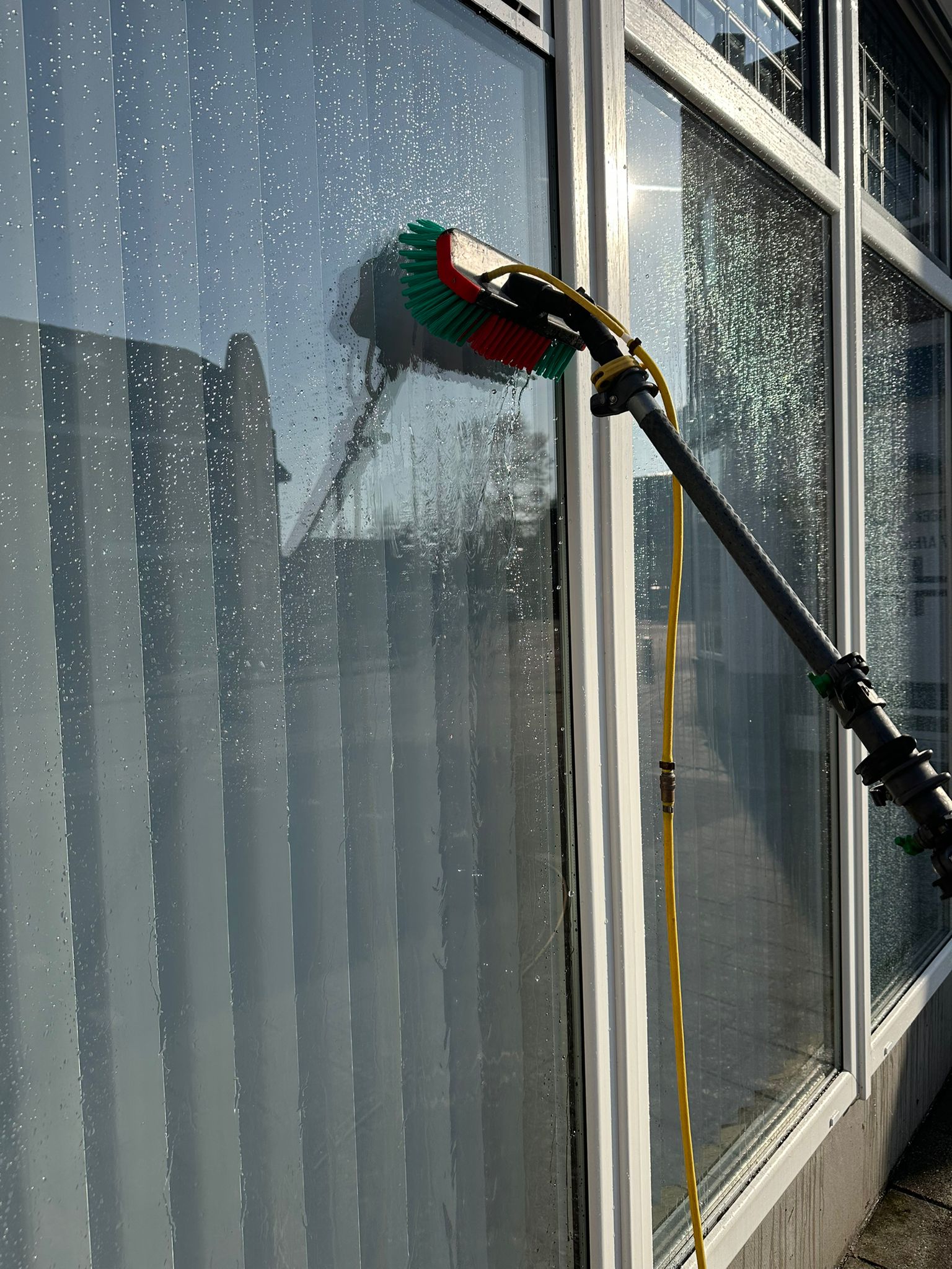 Glazenwasser aan het werk met telescoopsteel